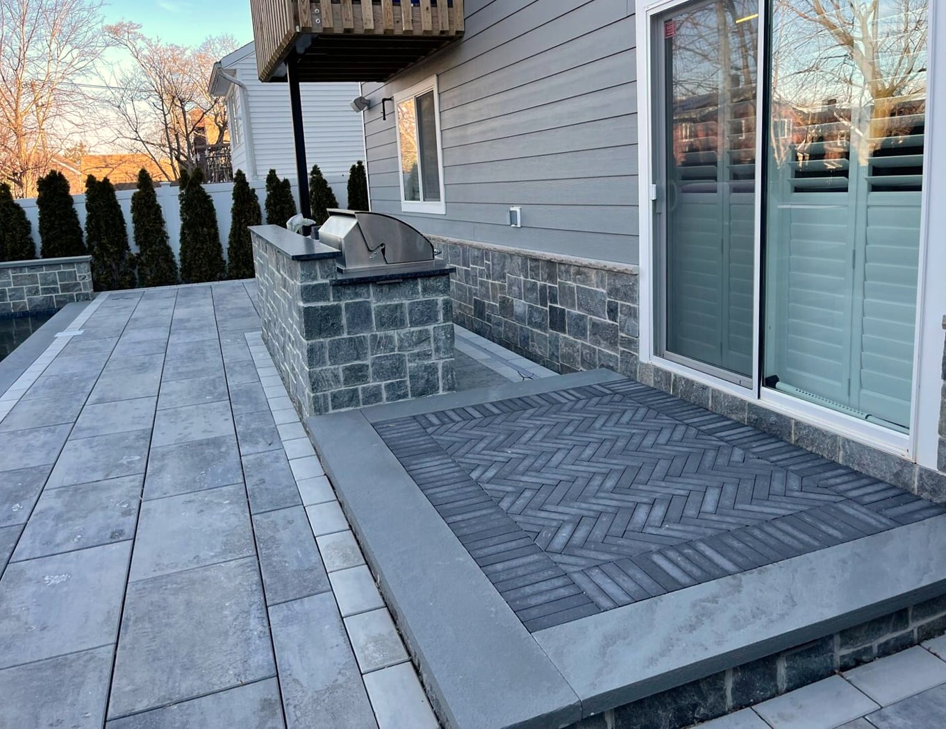 Paver patio with built-in stone grill station and herringbone inlay